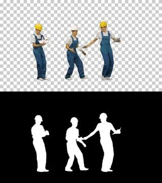 Three young construction workers in hardhats passing on document Foto stock