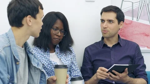 Three young creative people discussing ideas over coffee Video stock 105189152