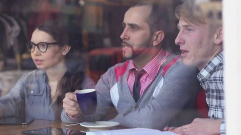 Three young, creative people met in a cafe and discussing project Stock-Footage 85224093