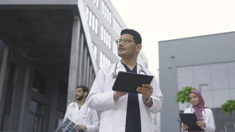 Three young doctors, working with tablet pc, xray and patient's medical record Stock Footage 157478122