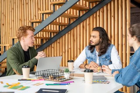 Three young educated developers of software discussing their ideas at meeting Stock Photos