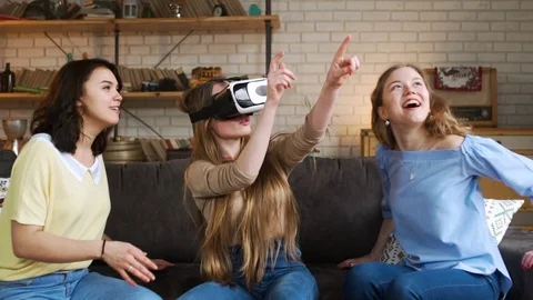 Three young energetic girlfriends laugh and move funny using together VR device Stock Footage 75568034