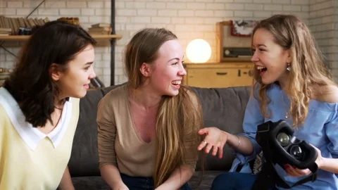 Three young energetic girlfriends laugh and move funny using together VR device Stock Footage 75612728