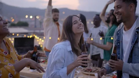 Three young excited multi-ethnic friends dance at rooftop barbecue party Stock Footage 244596807