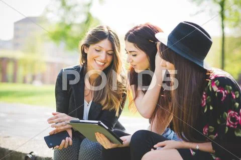 Three Young Female Friends Sharing Update On Digital Tablet In Park