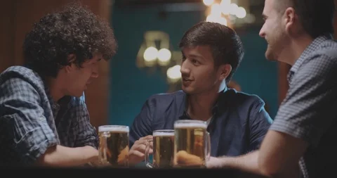 Three young friends drinking beer in bar or pub 4k dollyshot Stock Footage 90798815