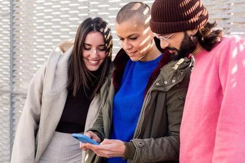 Three young friends enjoying using phone together Stock Photos