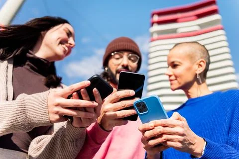 Three young friends having fun using mobile phones Stock Photos