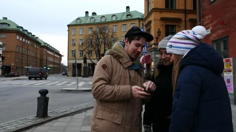 Three young friends looking at city map in smartphone, planning where to go in Stock Footage 60645409