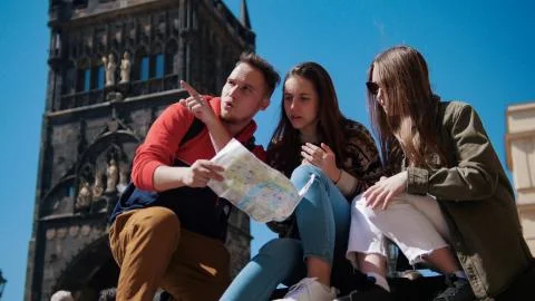 Three young friends navigate the map and looking right path under the old tower Stock Photos