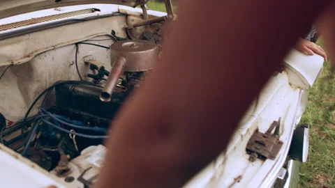 Three young friends open the engine of a vintage white car after it breaks down Stock Footage 199462206