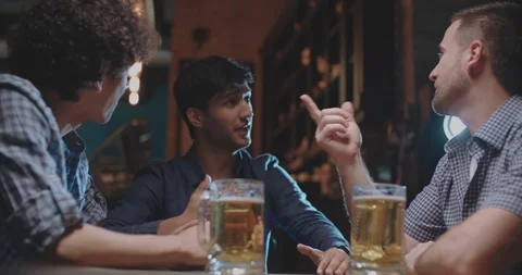 Three young friends talking then drinking beer in pub 4k dollyshot Vídeo Stock 90810507
