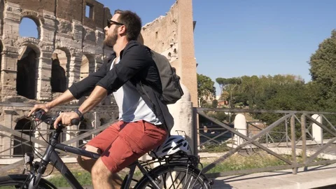 Three young friends tourists riding bikes on road around Colosseum in Rome city Stock Footage