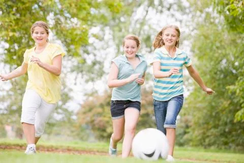 Three young girl friends playing soccer Stock Photos