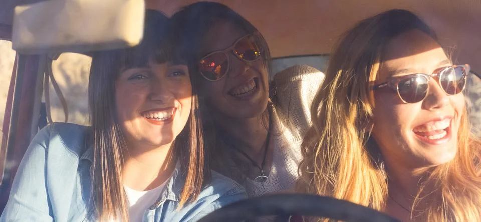 Three young girls women having fun and laughing a lot inside a car in drivi.. Stock Photos