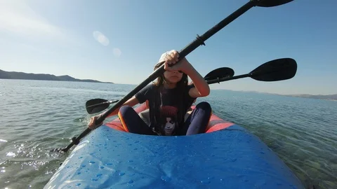 Three young Kayakers paddle on inflatable kayak in clear sea waters Video stock 130138880