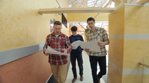 Three young men look at blueprint, discuss, move Stock Footage 64182330