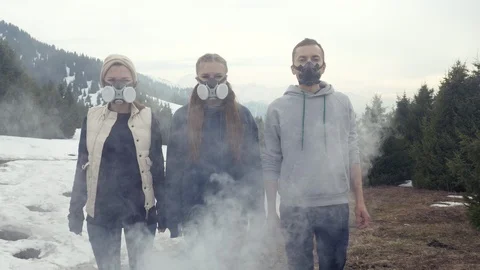 Three young men stand in gas masks bad air and smoke Vidéo 112286141