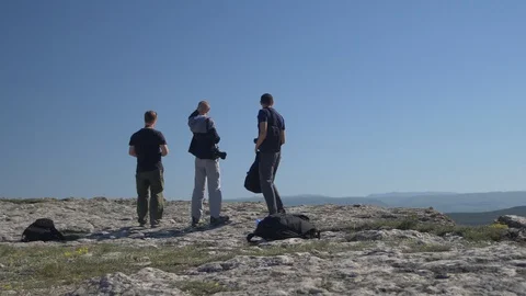Three young men stand on top of a mountain and look at the landscape Stock-Footage 90505602