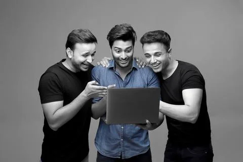 Three Young Models Are Looking At A Laptop Screen With A Surprised Smile 스톡 사진