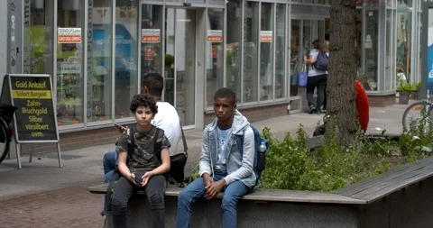 Three young multi ethnic boys sitting at the inner city of Duisburg, Germany 4K Stock Footage 110880776