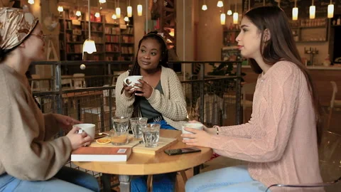 Three young multiethnic female friends spending time together at a coffee shop. Stock Footage 150582580