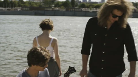 Three Young Musicians at the River Bank Stock Footage 90130735