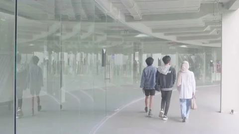 Three young people are walking beside a mirror that gives reflection Stock Footage 221979758