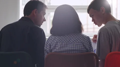 Three young people comparing notes in lecture hall Stock Footage 105190306