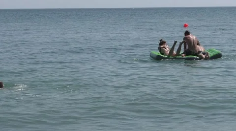 Three Young People Floating on Air Mattress on Sea Waves in Summer Stock Footage 65670566