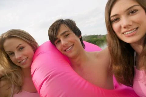 Three young people with rubber ring, smiling Stock Photos