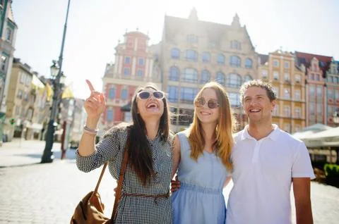 Three young people stand on the square of the ancient city. Stock Photos