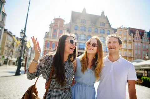 Three young people stand on the square of the ancient city. Stock Photos