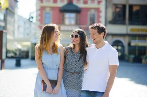 Three young people stand on the square of the ancient city. Stock Photos