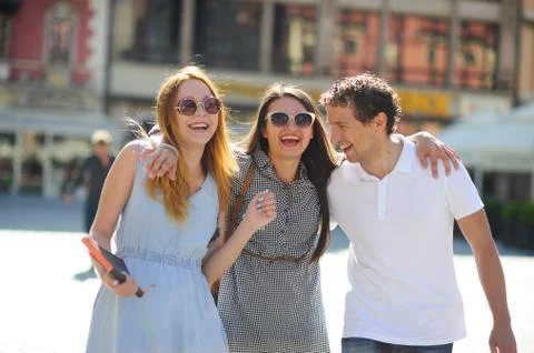 Three young people stand on the square of the ancient city. Stock Photos