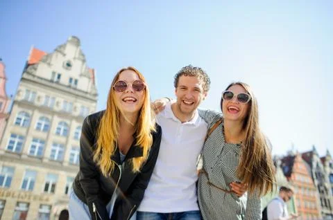 Three young people stand on the square of the ancient city. Stock Photos