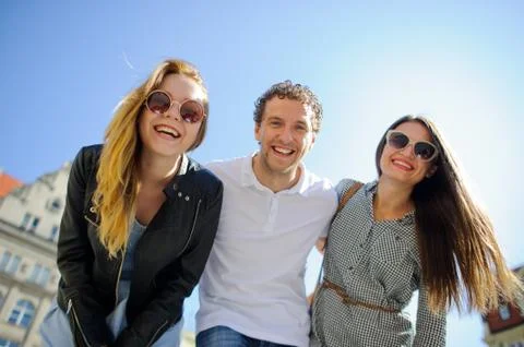 Three young people stand on the square of the ancient city. Stock Photos