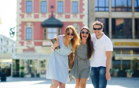 Three young people stand on the square of the ancient city. Stock Photos