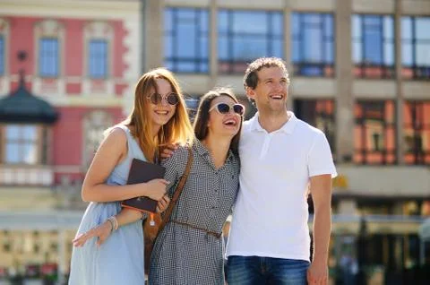Three young people stand on the square of the ancient city. Stock Photos