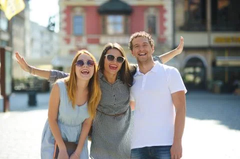 Three young people stand on the square of the ancient city. Stock Photos