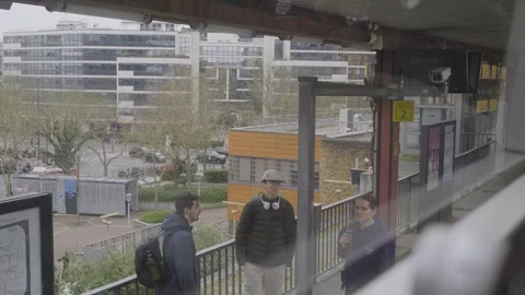 Three young people wait on a raised Paris platform with modern buildings behind Stock Footage 306237369