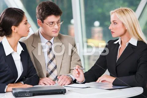 Three young professionals gathered together discussing important business plan i Stock Photos