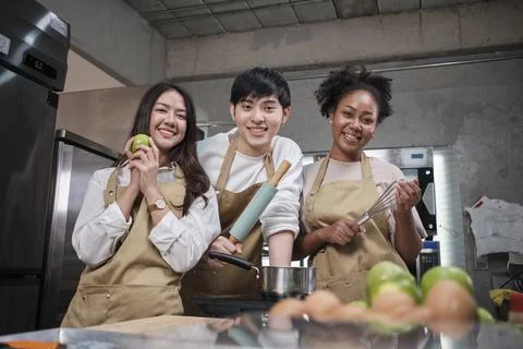 Three young students in cooking class wear aprons enjoy and cheerful and fun Stock Photos