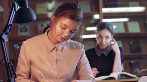 Three young students sitting in library and doing their business Stockbeeldmateriaal 73315513