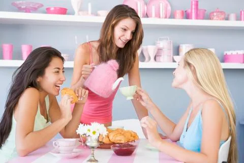Three young woman sitting at a table having tea and a snack Stock Photos