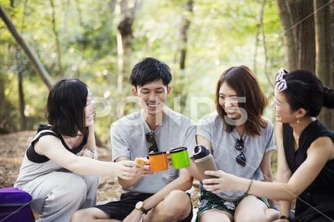 Three young women and a man sitting in a forest. Stock Photos