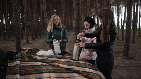 Three young women drinking tea on a picnic in the woods near the car Stock Footage 131360480