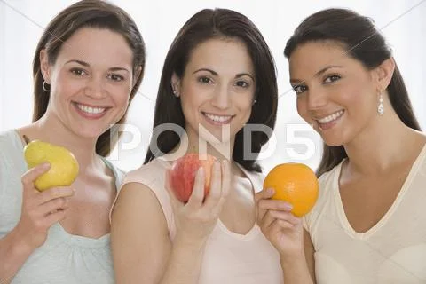 Three young women holding fruit Stock Photos