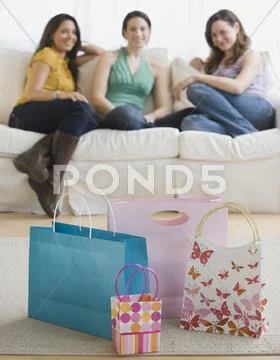 Three young women looking at gift bags Stock Photos