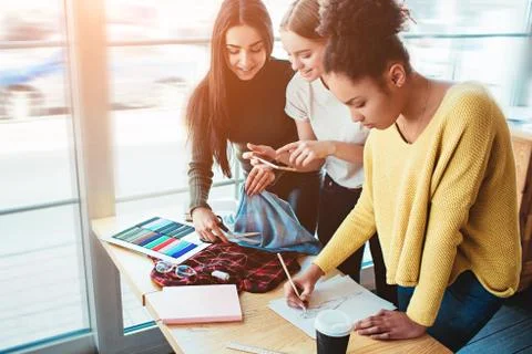 Three young women standing together and working for the same fashion project Stockfoto's